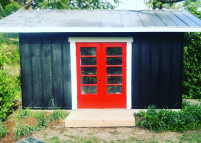 Black shed with red doors and angled roofing BNH Builders